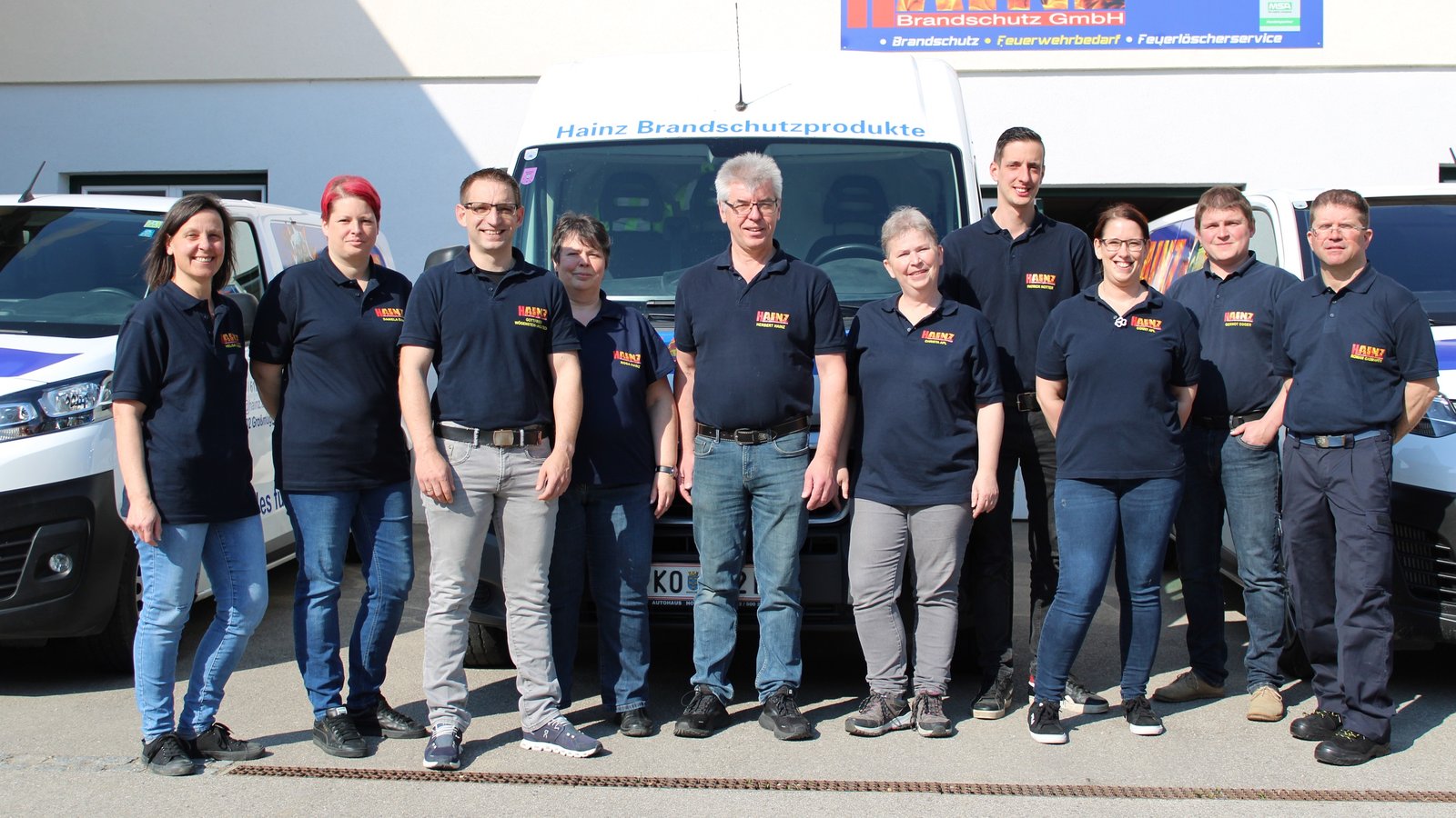 Team von HAINZ Brandschutz vor den Firmenwagen am Betriebsgebäude