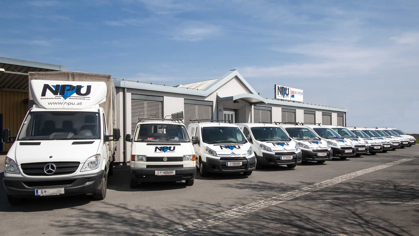 Firmenwagen von NPU Elektrotechnik in einer Reihe vor dem Betriebsgebäude