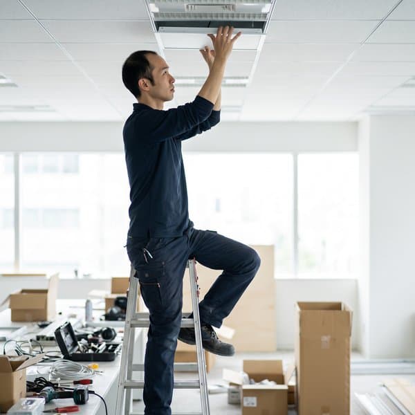Elektriker setzt eine LED-Leuchte in eine Bürodecke