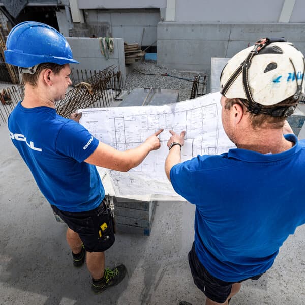 Zwei Mitarbeiter von Doll besprechen auf der Baustelle den Plan
