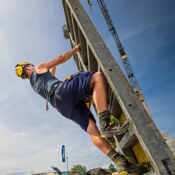 Mitarbeiter von Doll klettert an einer Schaltafel auf der Baustelle