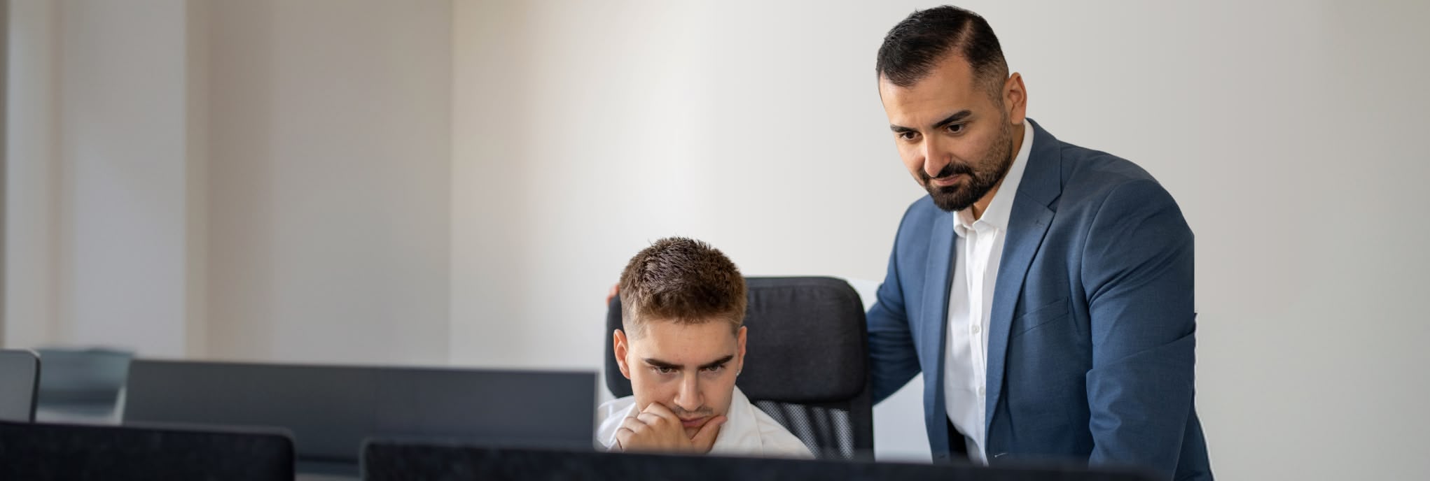 Yunus Emre Akkaya erklärt einem Mitarbeiter im Büro von YeaMedia etwas am Bildschirm